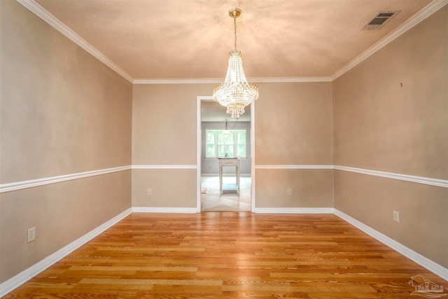 spare room with ornamental molding, a chandelier, and hardwood / wood-style flooring