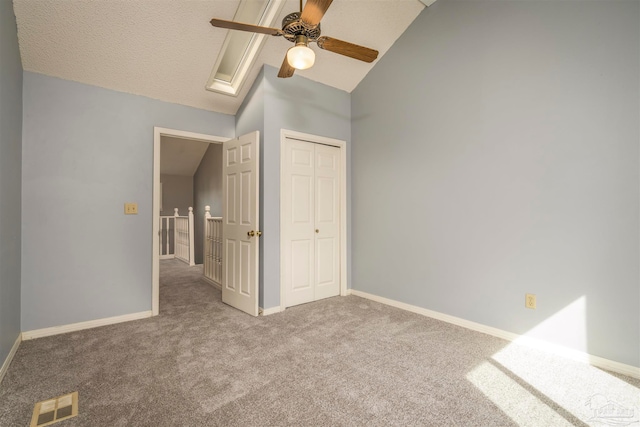 unfurnished bedroom with a closet, a textured ceiling, carpet floors, a skylight, and ceiling fan