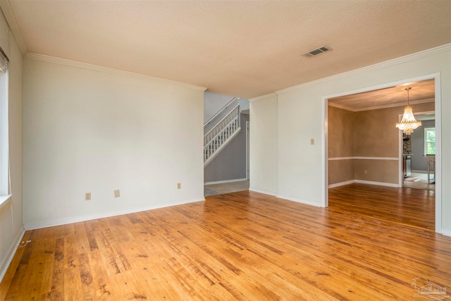 unfurnished living room with ornamental molding, a chandelier, a textured ceiling, and hardwood / wood-style flooring