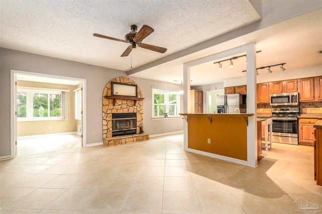 kitchen with a breakfast bar, a textured ceiling, appliances with stainless steel finishes, and a healthy amount of sunlight