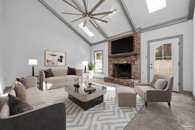 carpeted living room featuring high vaulted ceiling, a skylight, a ceiling fan, baseboards, and a brick fireplace