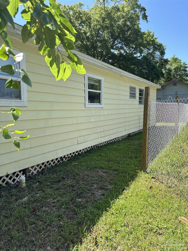 view of side of home with fence and a lawn