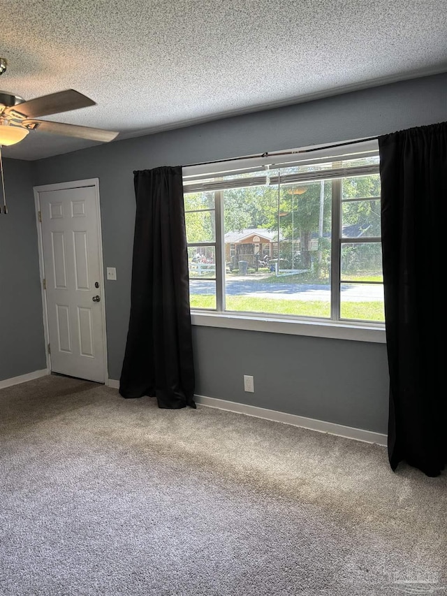 carpeted spare room with ceiling fan, a textured ceiling, and baseboards