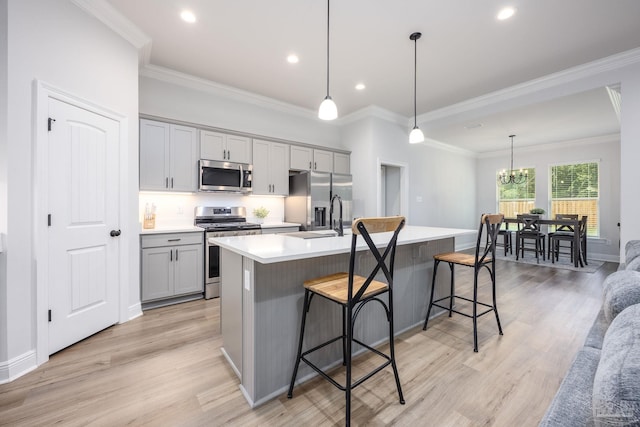 3248 Mountain Laurel Trl, Cantonment, FL 32533 - kitchen featuring appliances with stainless steel finishes, gray cabinets, an island with sink, a breakfast bar, and light wood-style flooring