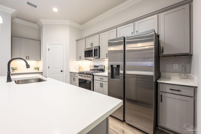 3248 Mountain Laurel Trl, Cantonment, FL 32533 - kitchen featuring appliances with stainless steel finishes, gray cabinets, crown molding, light countertops, and light wood-style flooring