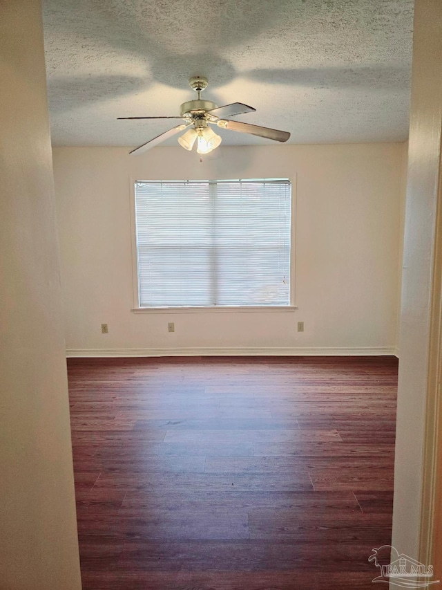 spare room featuring ceiling fan, dark hardwood / wood-style flooring, a textured ceiling, and a wealth of natural light