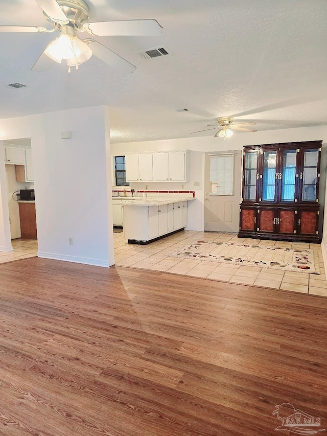 unfurnished living room featuring ceiling fan and light hardwood / wood-style flooring