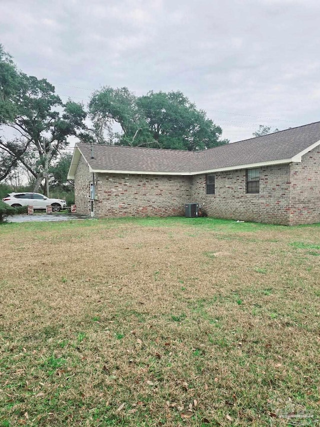 exterior space with central AC and a lawn