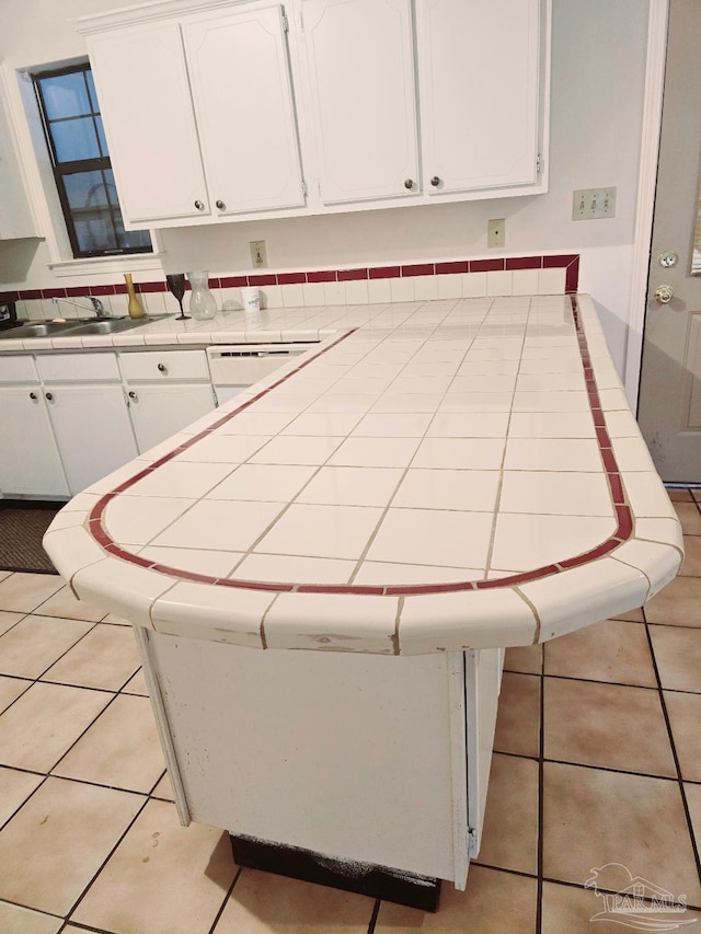 interior space with tile counters, sink, and white cabinets