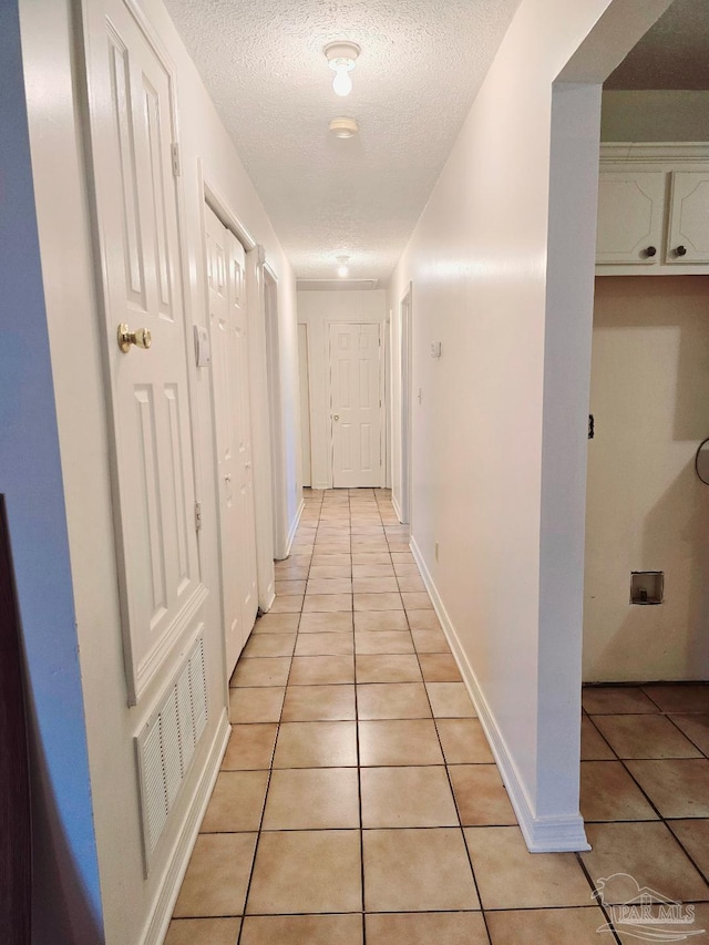 hallway featuring light tile patterned flooring and a textured ceiling