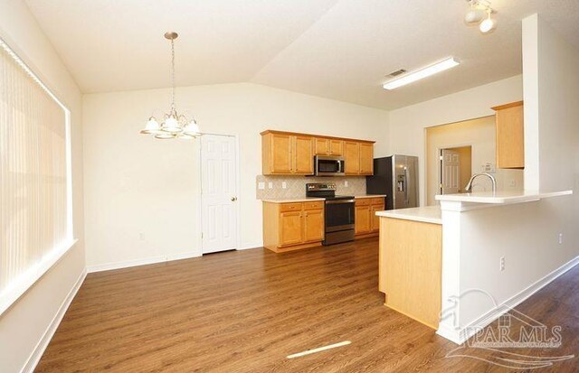 8679 High School Blvd, Navarre, FL 32566 - kitchen with stainless steel appliances, a peninsula, vaulted ceiling, decorative backsplash, and dark wood-style floors