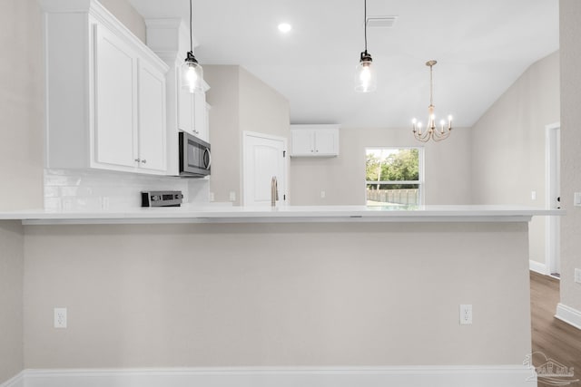 7917 Twin Lake Dr, Milton, FL 32583 - kitchen with stainless steel microwave, light countertops, white cabinets, a peninsula, and dark wood-type flooring