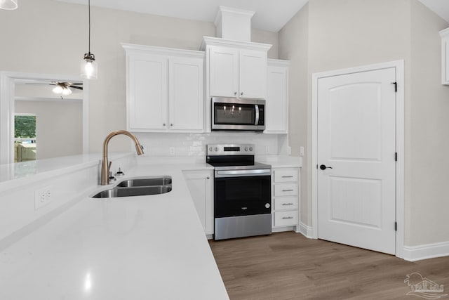 7917 Twin Lake Dr, Milton, FL 32583 - kitchen featuring appliances with stainless steel finishes, white cabinetry, light wood-type flooring, light countertops, and a ceiling fan