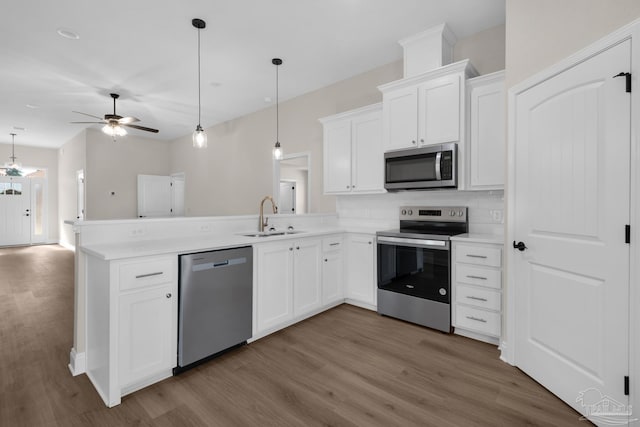 7917 Twin Lake Dr, Milton, FL 32583 - kitchen with appliances with stainless steel finishes, wood finished floors, a ceiling fan, and a peninsula