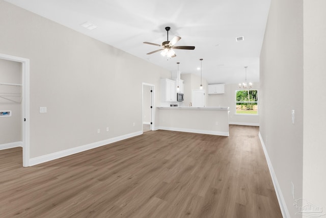 7917 Twin Lake Dr, Milton, FL 32583 - unfurnished living room featuring a ceiling fan, a chandelier, light wood-style floors, and vaulted ceiling