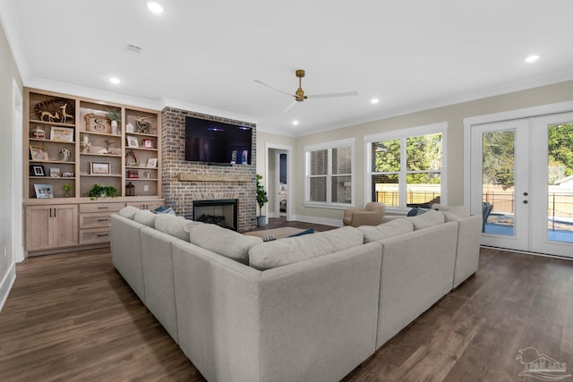 living room featuring crown molding, dark hardwood / wood-style flooring, french doors, built in features, and a brick fireplace