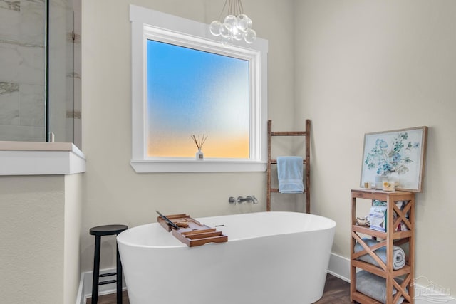 bathroom with hardwood / wood-style flooring, a baseboard heating unit, a tub to relax in, and a notable chandelier