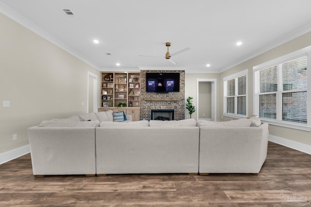 living room with dark hardwood / wood-style flooring, a fireplace, built in features, ornamental molding, and ceiling fan