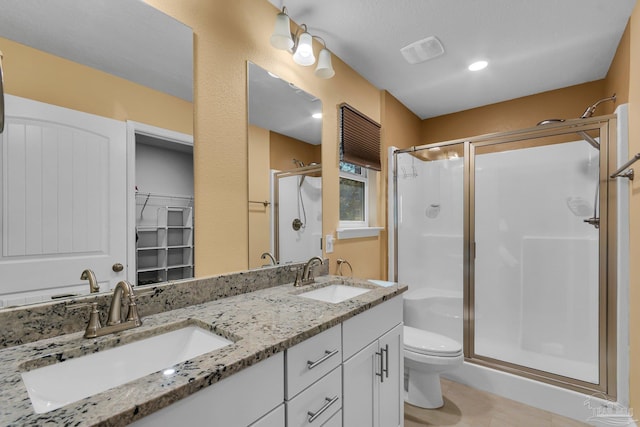 full bathroom with toilet, a sink, double vanity, and a shower stall