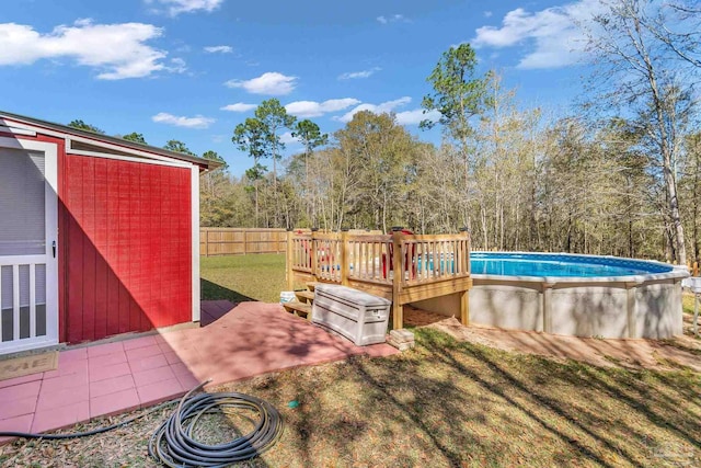 view of yard featuring a deck, an outdoor pool, fence, and a patio
