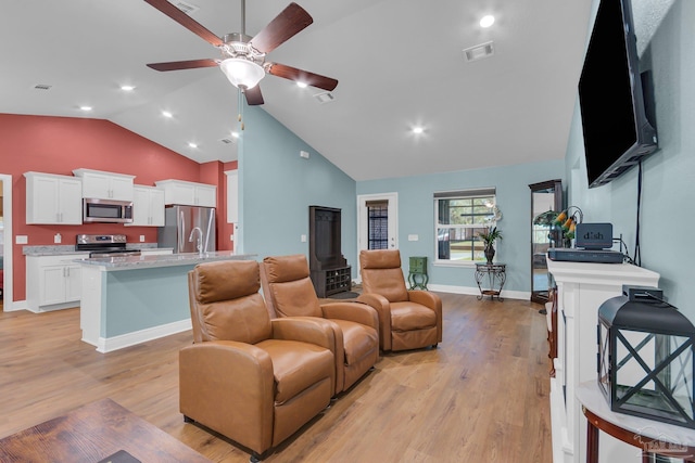 living room featuring light wood-style flooring, vaulted ceiling, ceiling fan, and visible vents