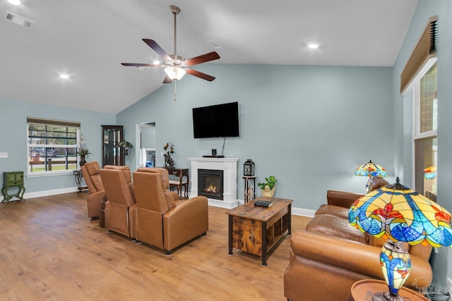 living room featuring a ceiling fan, a lit fireplace, light wood-style flooring, and visible vents