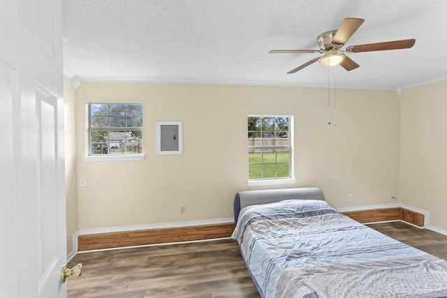 bedroom featuring wood finished floors, baseboards, electric panel, a textured ceiling, and crown molding