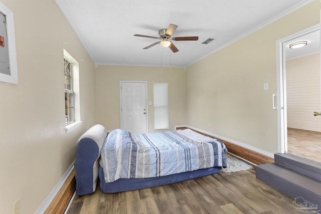 bedroom with visible vents, wood finished floors, crown molding, baseboards, and ceiling fan