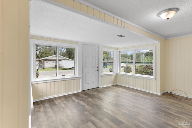 unfurnished room featuring a wealth of natural light, a textured ceiling, and wood finished floors