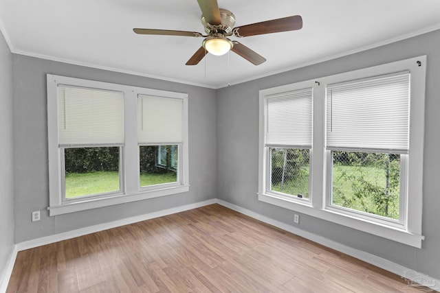 spare room featuring ceiling fan, baseboards, light wood-style flooring, and crown molding