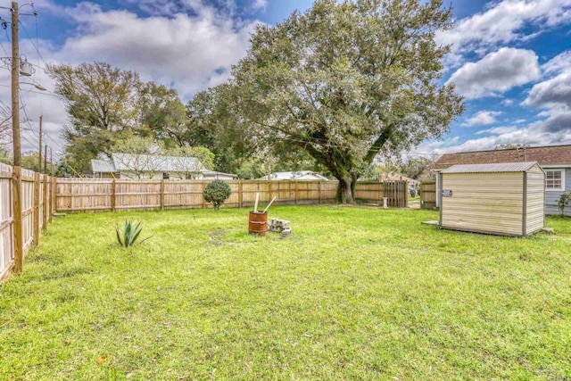 view of yard featuring a storage unit, a fenced backyard, and an outdoor structure