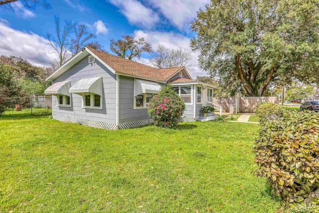 view of property exterior featuring a lawn and fence