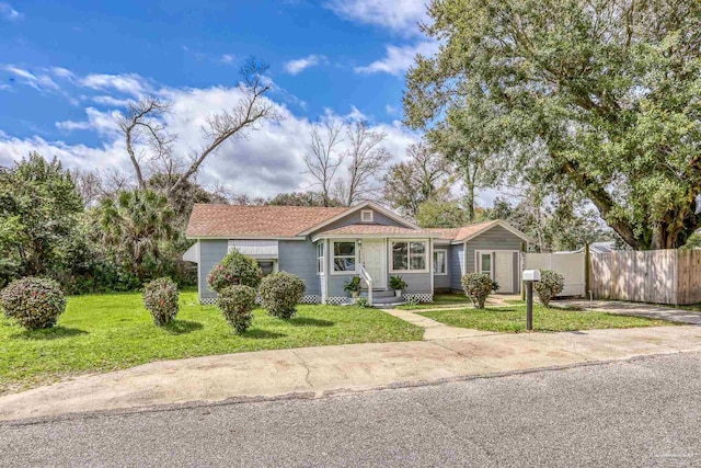 ranch-style home featuring entry steps, a front lawn, and fence