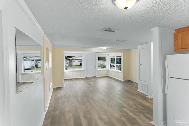 interior space featuring crown molding, a textured ceiling, freestanding refrigerator, and dark wood-type flooring