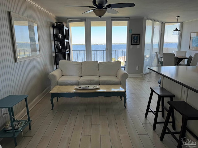 living room featuring ceiling fan, crown molding, a water view, and light wood-type flooring