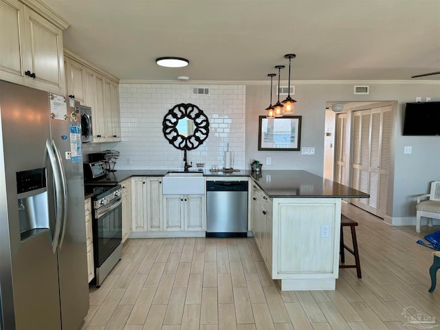 kitchen with kitchen peninsula, appliances with stainless steel finishes, a kitchen breakfast bar, backsplash, and pendant lighting