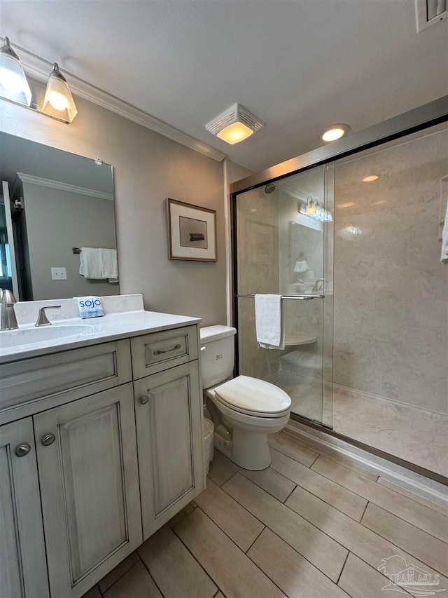 bathroom with toilet, an enclosed shower, ornamental molding, and vanity