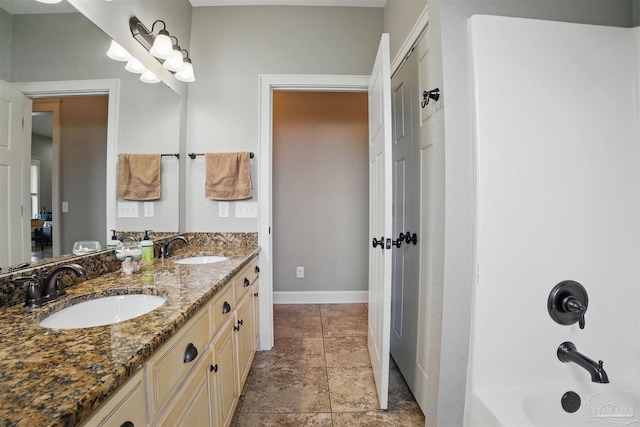 full bath with double vanity, baseboards, bathtub / shower combination, and a sink