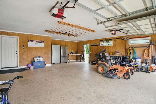 garage with wood walls, a garage door opener, and freestanding refrigerator