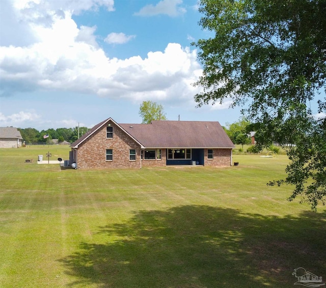 back of house with a lawn and brick siding