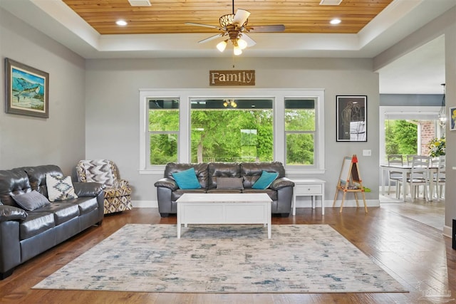 living area featuring wooden ceiling, ceiling fan, and a raised ceiling