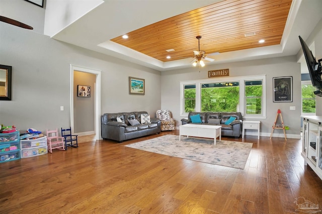 living area with wood ceiling, a ceiling fan, and a tray ceiling