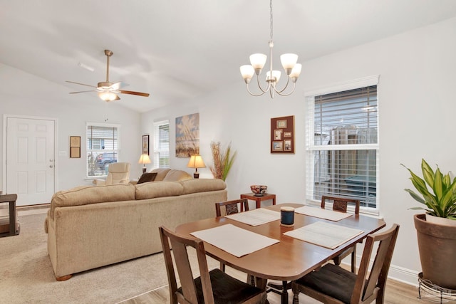 dining area featuring lofted ceiling, ceiling fan with notable chandelier, and light hardwood / wood-style flooring