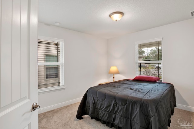 bedroom with light colored carpet and a textured ceiling