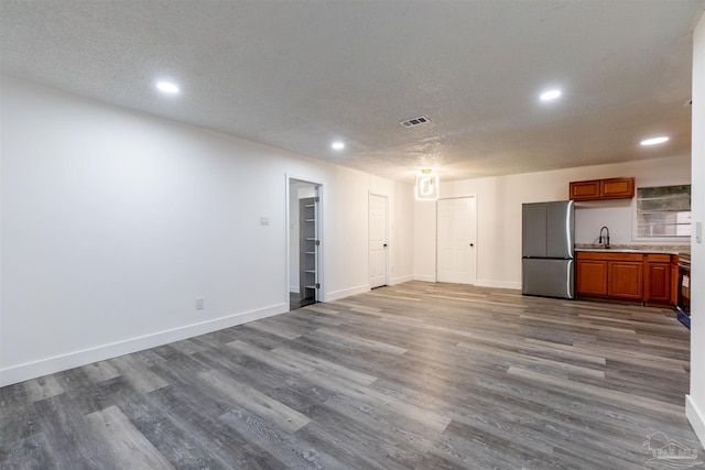 unfurnished living room featuring hardwood / wood-style floors, a textured ceiling, and sink