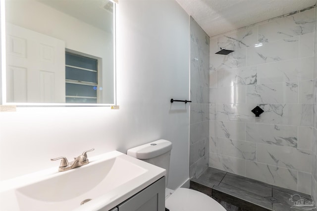 bathroom with a tile shower, vanity, a textured ceiling, and toilet