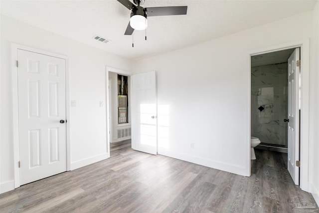 unfurnished bedroom with hardwood / wood-style floors, ceiling fan, a textured ceiling, and ensuite bath