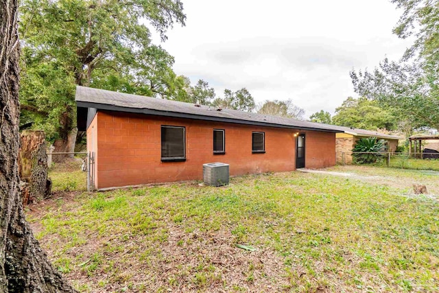 back of property featuring central AC and a yard