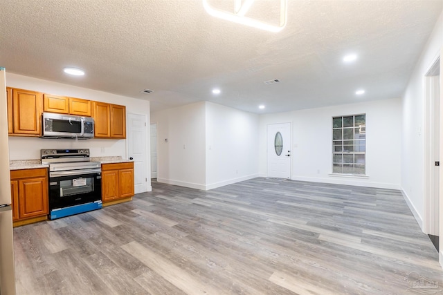 kitchen featuring a textured ceiling, appliances with stainless steel finishes, and light hardwood / wood-style flooring