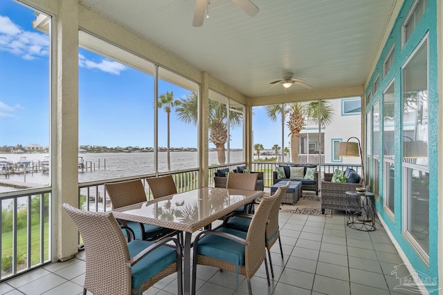 sunroom / solarium featuring ceiling fan and a water view